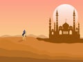 A man riding a camel in the desert has a mosque behind it.