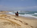 A man riding on a camel on an empty beach