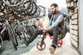 Man riding children`s bicycle in the store Royalty Free Stock Photo