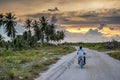 The man riding cycle on the road during sunset time at the tropical island