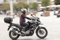 Man riding a fast motorbike with rear box in empty street by city square, panning shot