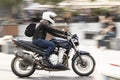 Man riding a fast motorbike on the street by city square, panning shot