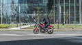 man riding fast on red motorbike Ducati. Rider in black clothes and helmet, driving on city street on a sunny day Royalty Free Stock Photo