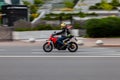 man riding fast on red motorbike Ducati. Rider in casual clothes and a yellow helmet, driving on city street on high speed. City
