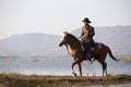 Cowboy on his horse walking through dust in the lake