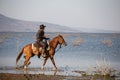 Cowboy on his horse walking through dust in the lake Royalty Free Stock Photo