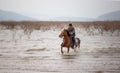 Man riding horse in lake against sunset and mountain Royalty Free Stock Photo