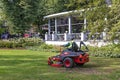 Man on a riding lawn mower that has grass stuck to the wheels Royalty Free Stock Photo