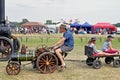 A man riding a mini steam engine with a trailer on the back pulling two small children on the back Royalty Free Stock Photo