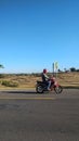 a man riding a motorbike on a rice field road that has been dry due to the dry season