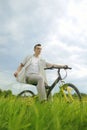 The man is riding a mountain bike. A fashionable guy came to nature in the field. The guy on the background of nebt. Bright yellow Royalty Free Stock Photo