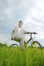 The man is riding a mountain bike. A fashionable guy came to nature in the field. The guy on the background of nebt. Bright yellow Royalty Free Stock Photo