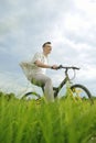 The man is riding a mountain bike. A fashionable guy came to nature in the field. The guy on the background of nebt. Bright yellow Royalty Free Stock Photo