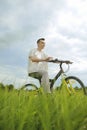 The man is riding a mountain bike. A fashionable guy came to nature in the field. The guy on the background of nebt. Bright yellow Royalty Free Stock Photo