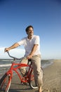 Man riding red bicycle on beach.