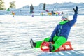 A man riding on a red sled descends down the mountain