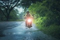 man riding small endurom motorcycle crossing shallow creek among rain falling at forest