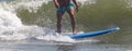 Man riding a wave surfing on a blue surfboard
