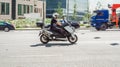 Man riding on Yamaha TMAX maxi-scooter on urban highway road. Biker on scooter speeding through the street of the city