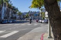 A man riding a yellow dirt bike on the street with parked cars, lush green palm trees, apartments and shops in Hollywood Royalty Free Stock Photo