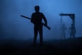 Man with riffle against zombie attack. Zombie apocalypse. Scary view of blurred zombies at cemetery and spooky cloudy sky with fog Royalty Free Stock Photo