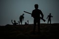 Man with riffle against zombie attack. Zombie apocalypse. Scary view of blurred zombies at cemetery and spooky cloudy sky with fog Royalty Free Stock Photo