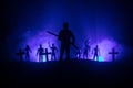 Silhouettes crowd of hungry zombies and old windmill on hill against dark foggy toned sky. Silhouettes of scary zombies walking at