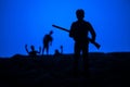 Man with riffle against zombie attack. Zombie apocalypse. Scary view of blurred zombies at cemetery and spooky cloudy sky with fog