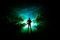 Man with riffle at spooky forest at night. Strange silhouette of hunter in a dark spooky forest at night, mystical landscape surre