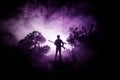 Man with riffle at spooky forest at night. Strange silhouette of hunter in a dark spooky forest at night, mystical landscape surre