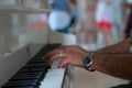 Man with a ring on his finger and a watch on his wrist plays piano