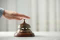 Man ringing hotel service bell at table indoors. Space for text Royalty Free Stock Photo