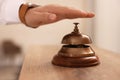 Man ringing service bell at wooden reception desk in hotel, closeup Royalty Free Stock Photo