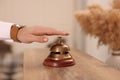 Man ringing service bell at wooden reception desk in hotel, closeup Royalty Free Stock Photo