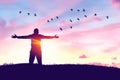 Man rising hands and birds flying on sunset sky at nature field abstract background. Freedom feel good and travel adventure