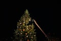 Man on the rising platform gigantic crane decorating Christmas tree