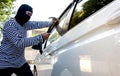 The man robber with a balaclava on his head holding a hammer trying to break into the car Royalty Free Stock Photo