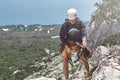 Man rock climber on the top of the cliff and belays a partner