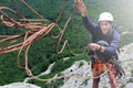 Man rock climber on the top of the cliff and throws a rope to a partner