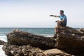 Man on a rock at pointing at the sea