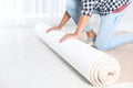 Man rolling out new carpet flooring indoors, closeup. Royalty Free Stock Photo