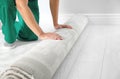 Man rolling out new carpet flooring indoors, closeup. Royalty Free Stock Photo