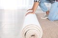 Man rolling out new carpet flooring indoors, closeup. Royalty Free Stock Photo