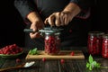 A man rolls up a jar of ripe raspberries for canning using a manual seaming key. The concept of making raspberry jam or compote in Royalty Free Stock Photo