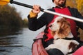 Man rowing a canoe with his spaniel dog, sunny autumn weather.