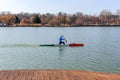 Man rowing in canoe with paddle , standing on one knee. Athlete trains on the lake