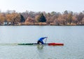 Man rowing in canoe with paddle , standing on one knee. Athlete trains on the lake