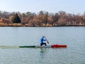 Man rowing in canoe with paddle , standing on one knee. Athlete trains on the lake