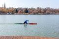 Man rowing in canoe with paddle , standing on one knee. Athlete trains on the lake