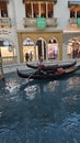 A man rowing a gondola on rippling blue water with people walking at The Venetian hotel and resort in Las Vegas Nevada Royalty Free Stock Photo